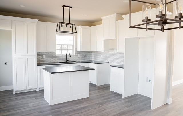 kitchen with hanging light fixtures, sink, white cabinets, a kitchen island, and light hardwood / wood-style floors