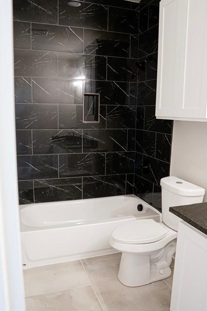 full bathroom featuring vanity, toilet, tiled shower / bath combo, and tile patterned flooring