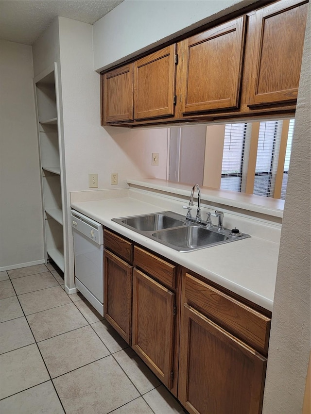 kitchen with white dishwasher, sink, light tile patterned floors, and a textured ceiling