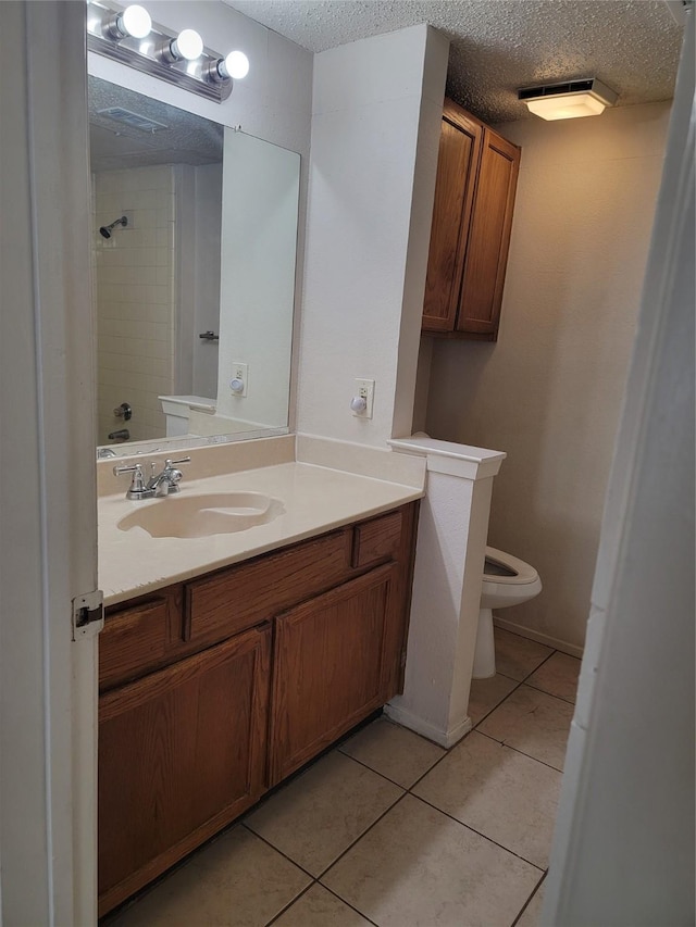 bathroom featuring vanity, toilet, tile patterned flooring, and a textured ceiling