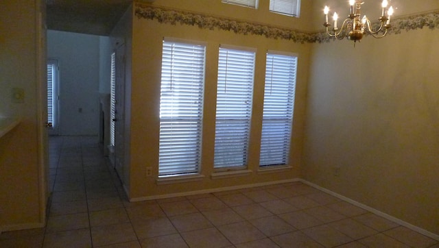 tiled spare room featuring a notable chandelier