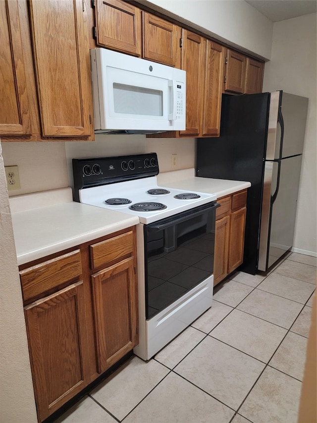 kitchen with light tile patterned floors, range with electric stovetop, and stainless steel fridge