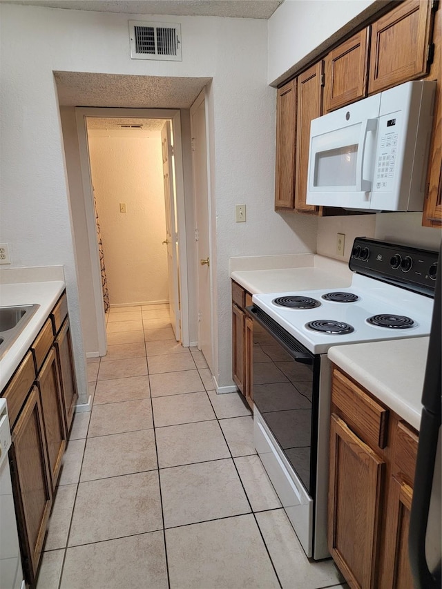 kitchen with light tile patterned floors, white appliances, and sink