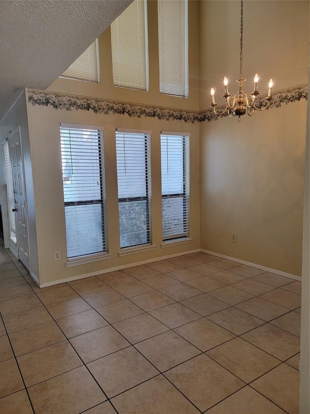 spare room with high vaulted ceiling, a chandelier, light tile patterned floors, and a textured ceiling