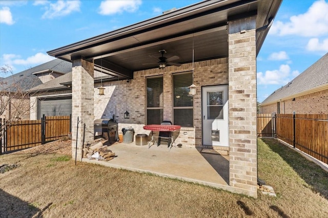 rear view of house with ceiling fan, a patio, and a lawn