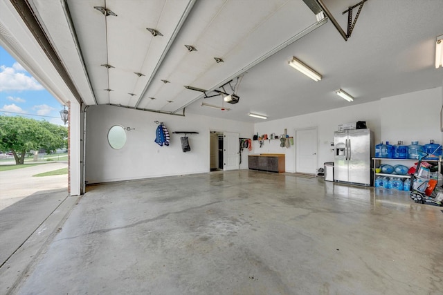 garage with a garage door opener and stainless steel fridge