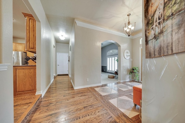 hall with crown molding, a chandelier, and light hardwood / wood-style flooring