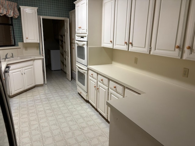 kitchen featuring white cabinetry, sink, and multiple ovens