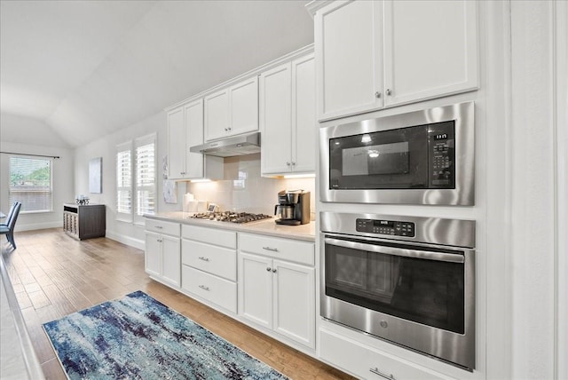 kitchen featuring white cabinetry, vaulted ceiling, light hardwood / wood-style flooring, and appliances with stainless steel finishes