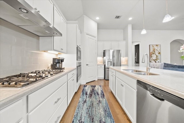 kitchen with sink, white cabinetry, backsplash, hanging light fixtures, and stainless steel appliances