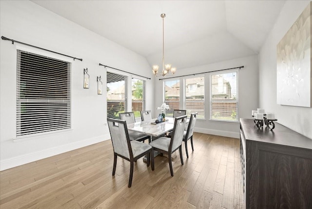 dining space featuring an inviting chandelier, vaulted ceiling, and light hardwood / wood-style flooring