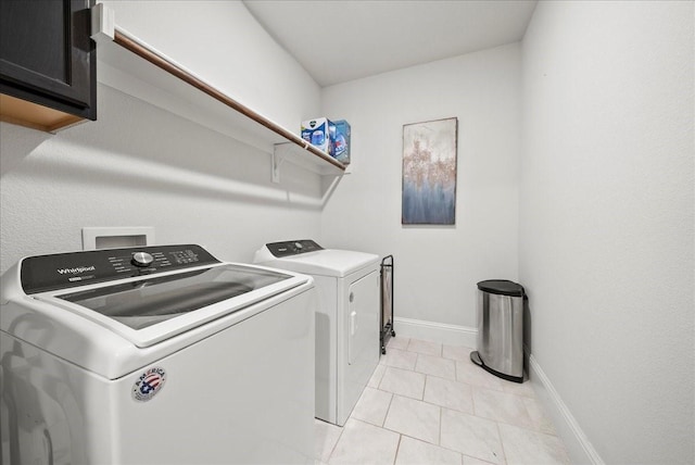 laundry room featuring independent washer and dryer, cabinets, and light tile patterned flooring