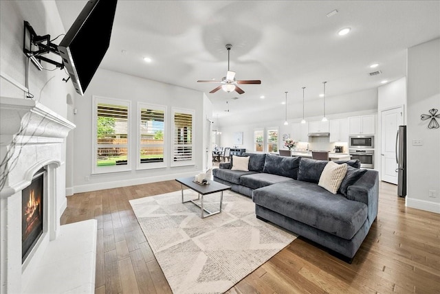 living room with light hardwood / wood-style flooring, a wealth of natural light, and ceiling fan