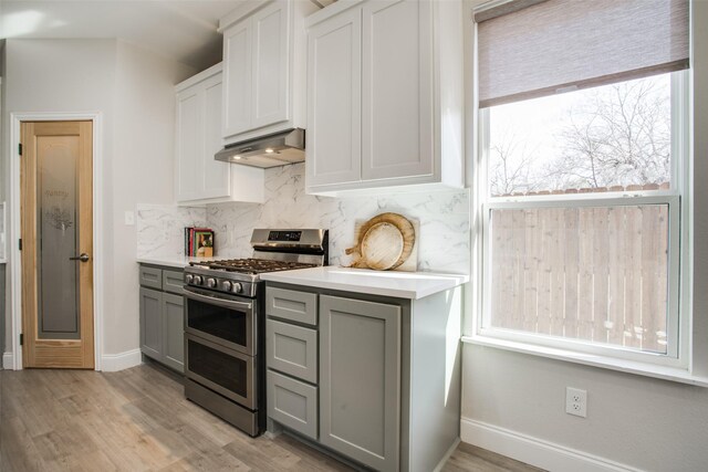 kitchen featuring a kitchen bar, appliances with stainless steel finishes, an island with sink, pendant lighting, and white cabinets