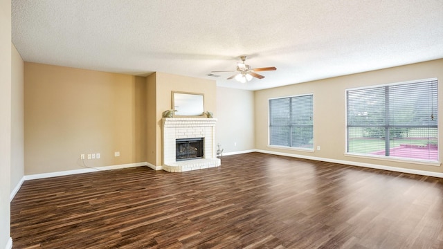 unfurnished living room featuring ceiling fan, dark wood-type flooring, a textured ceiling, and a fireplace