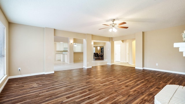 unfurnished living room with a textured ceiling, dark hardwood / wood-style floors, and ceiling fan