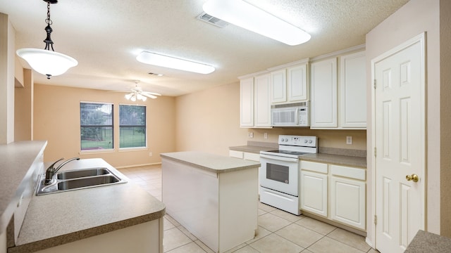 kitchen featuring sink, decorative light fixtures, a textured ceiling, a kitchen island, and white appliances