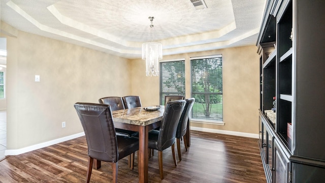 dining space with a tray ceiling, an inviting chandelier, baseboards, and dark wood-style floors