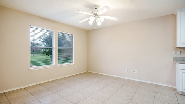 spare room with light tile patterned floors, baseboards, and ceiling fan