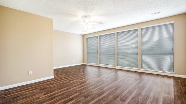 spare room with a ceiling fan, a textured ceiling, baseboards, dark wood finished floors, and visible vents