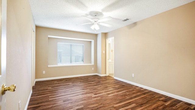 unfurnished room featuring a textured ceiling, baseboards, dark wood finished floors, ceiling fan, and visible vents