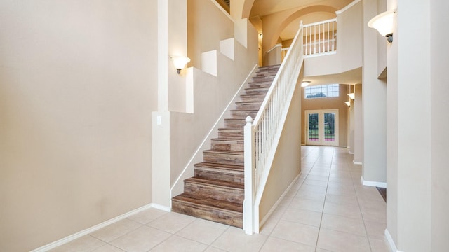 stairway with tile patterned floors and a high ceiling