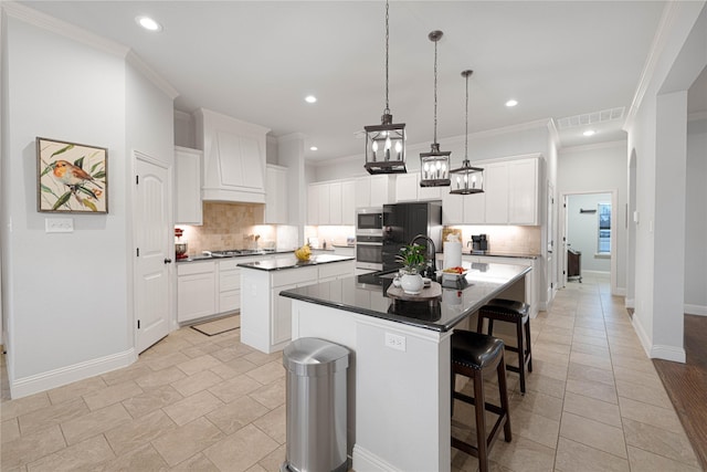 kitchen with a center island with sink, stainless steel appliances, white cabinetry, and hanging light fixtures