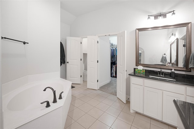 bathroom featuring tile patterned floors, lofted ceiling, vanity, and a bathing tub