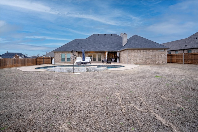 rear view of property featuring a fenced in pool and a patio area