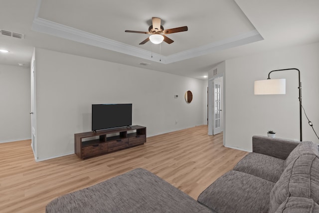 living room with a raised ceiling, crown molding, ceiling fan, and light hardwood / wood-style floors