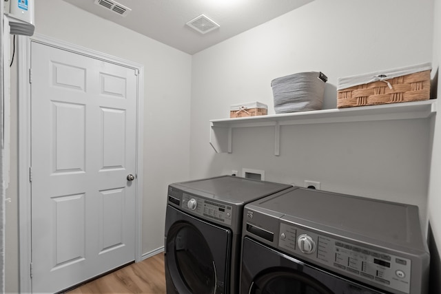 clothes washing area featuring light hardwood / wood-style flooring and washing machine and clothes dryer