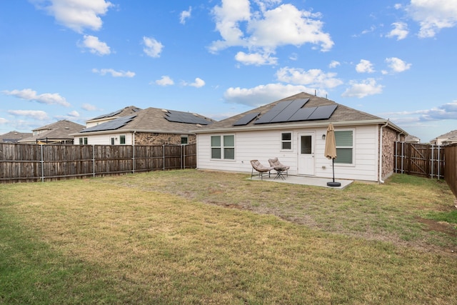 rear view of house featuring solar panels, a yard, and a patio area