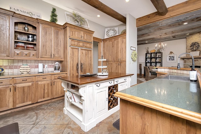 kitchen with wood counters, tasteful backsplash, a notable chandelier, paneled built in fridge, and beam ceiling