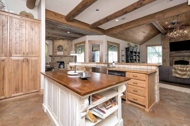 kitchen with dishwasher, a center island, a stone fireplace, and sink