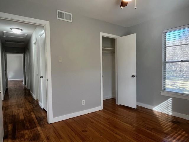 unfurnished bedroom featuring dark hardwood / wood-style floors, a closet, and ceiling fan