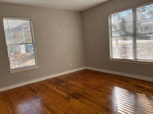 spare room with a healthy amount of sunlight and dark hardwood / wood-style flooring