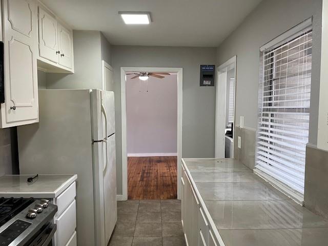 kitchen with white cabinetry, dark tile patterned flooring, ceiling fan, and gas range