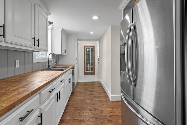 kitchen with butcher block countertops, sink, appliances with stainless steel finishes, white cabinetry, and dark hardwood / wood-style flooring