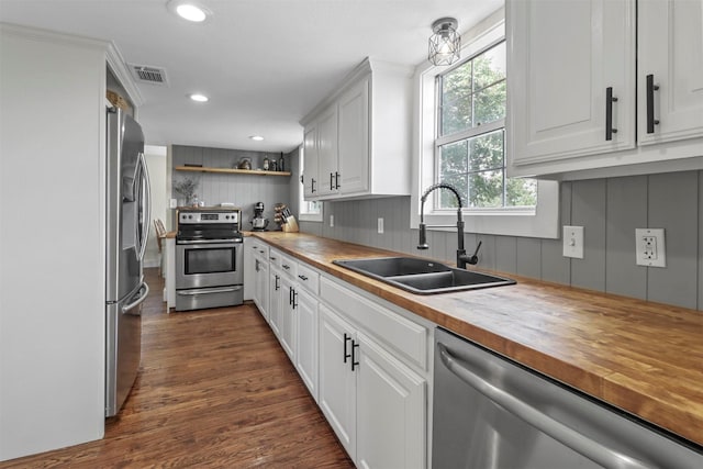 kitchen with dark hardwood / wood-style floors, sink, white cabinets, wooden counters, and stainless steel appliances