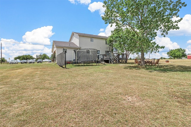 view of yard featuring a wooden deck and a trampoline