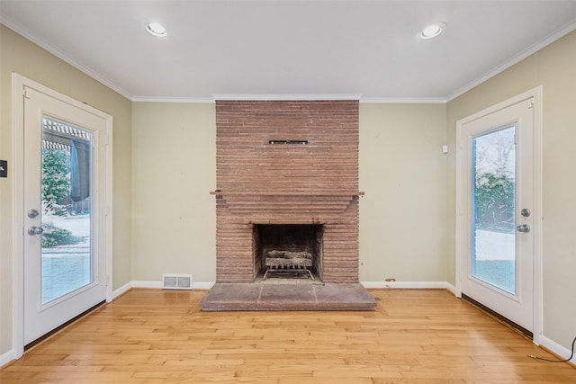 unfurnished living room with light hardwood / wood-style flooring, a fireplace, crown molding, and a wealth of natural light