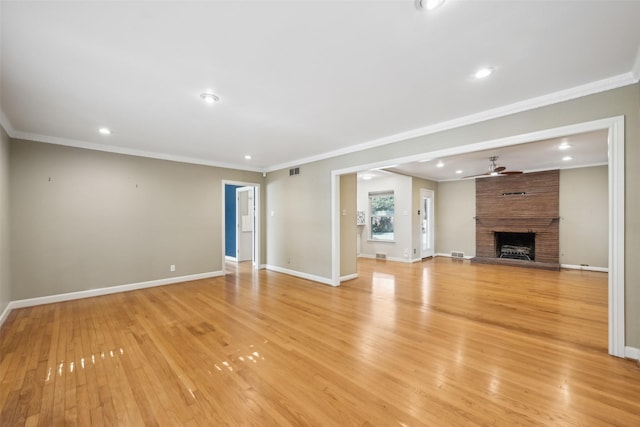 unfurnished living room with crown molding, a large fireplace, and light wood-type flooring