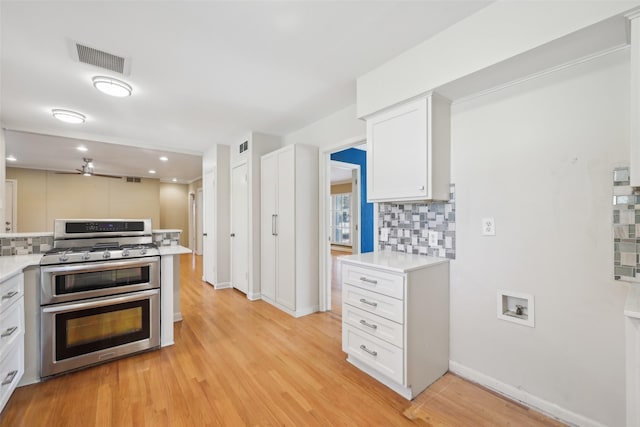 kitchen with white cabinetry, tasteful backsplash, light hardwood / wood-style floors, and range with two ovens