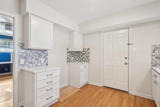 kitchen featuring decorative backsplash, light hardwood / wood-style floors, and white cabinets