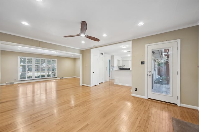 unfurnished living room featuring ornamental molding, ceiling fan, and light wood-type flooring