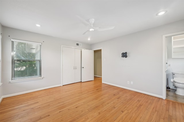 unfurnished bedroom featuring ensuite bath, light hardwood / wood-style flooring, a closet, and ceiling fan