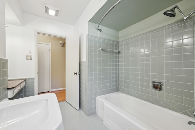 bathroom featuring tile patterned floors, tiled shower / bath combo, and tile walls