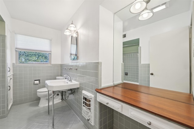 bathroom featuring heating unit, sink, tile walls, toilet, and tile patterned floors