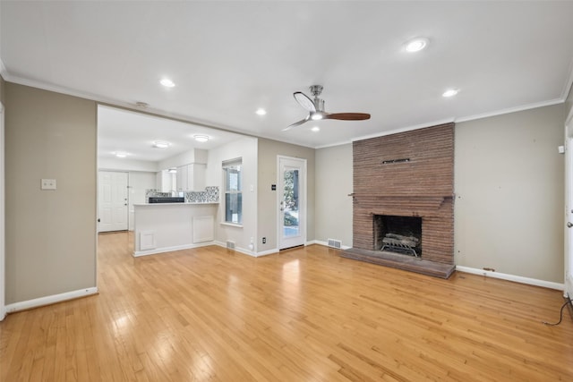 unfurnished living room with ceiling fan, ornamental molding, light hardwood / wood-style floors, and a brick fireplace