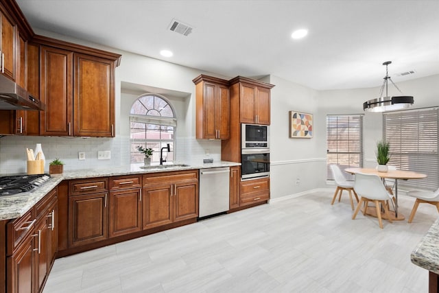 kitchen featuring stainless steel appliances, hanging light fixtures, sink, and decorative backsplash